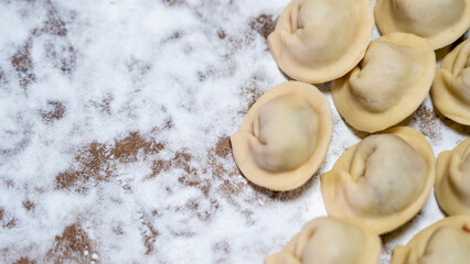 dumplings on a wooden board and flour on the background, homemade dumplings in close-up. natural products family traditions of cooking dumplings. High quality photo