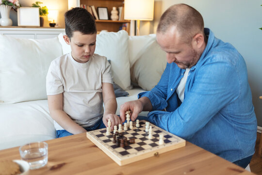 Excited, chess and father with boy, home and family with competition, proud and winner. Apartment, parent and dad with happy son, game and victory with cognitive development, challenge and checkmate.