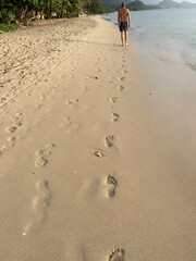 Footprints in the sand, the wave washes away the traces of bare feet