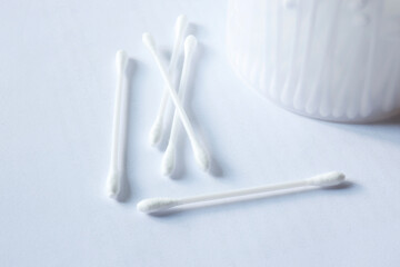 White cotton swabs on a light background with a container, ideal for themes of hygiene, healthcare, and personal care