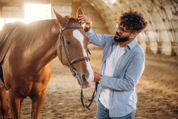 Spending time together indoors. Man is with horse in the hangar