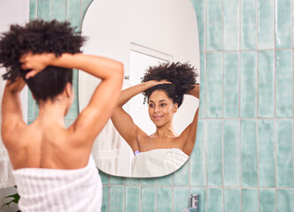 Woman With Natural Hair Ties Up In Bathroom Mirror To Start Her Morning Self-Care Routine