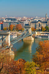 Obraz premium Budapest cityscape, panoramic view of city and Danube River with Chain bridge and beautiful architecture in autumn season, trees, branches and yellow leaves in foreground