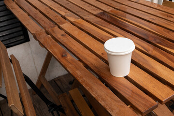 Coffee to go on wooden table, outdoors cafe. Takeaway white paper eco coffee cup