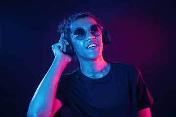 Listening to the music in headphones. Guy is indoors at night with neon lighting