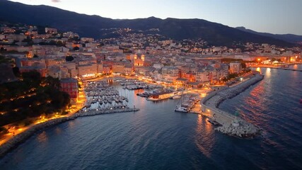 picturesque harbor during twilight hours, historic fortress overlooks tranquil water at evening. Bastia. France