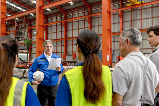 Supervisor of diverse engineers briefing his team before working in manufacturing factory. Leader giving a briefing to team in industrial site. Worker manager conducting a site meeting in a factory.
