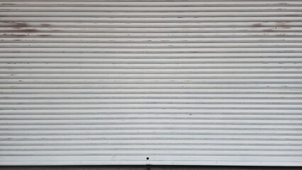 Rolling door with rust stains. Warehouse rolling steel door. Gray metal door panel. Steel rolling door background. Silver metal rolling door background. Background and texture images.