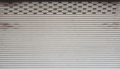 Rolling door with rust stains. Warehouse rolling steel door. Gray metal door panel. Steel rolling door background. Silver metal rolling door background. Background and texture images.
