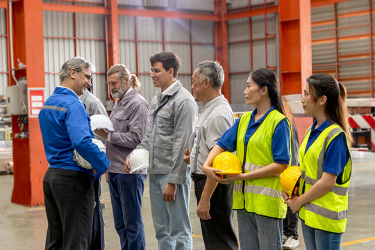 Supervisor of diverse engineers briefing his team before working in manufacturing factory. Leader giving a briefing to team in industrial site. Worker manager conducting a site meeting in a factory.