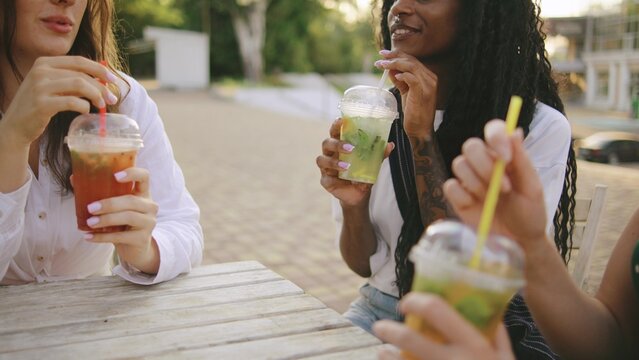 three female multiracial friends one disabled woman in a wheelchair enjoy refreshing drinks outdoors at a sunny gathering near a pool in late afternoon - Powered by Adobe