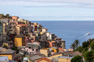 colourful buildings at manarola village at cinque terre liguria italy with boat leaving harbour