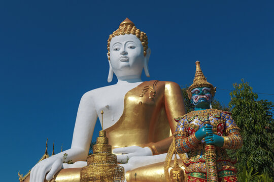 Chiang Mai, Thailand - November 23 2025 : A large white and gold sitting Buddha statue during afternoon at Wat Phra That Doi Kham, Chiang Mai.