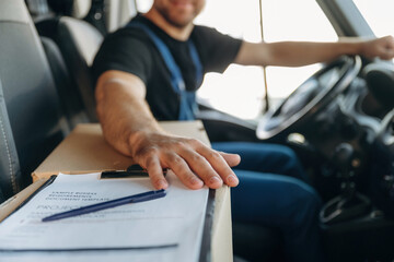 Naklejka premium Just formal stuff, the notepad with document, invoice. Inside of the bus with delivery service man in uniform