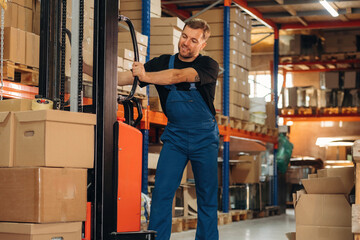 Moving stuff by using forklift. Man in uniform is working in the storage with packages for shipment