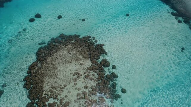 Aerial drone view of turquoise ocean water with coral reefs and gentle waves