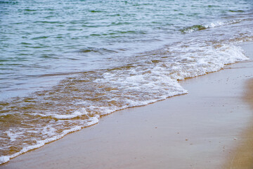 Soft baltic sea waves wash up on a sandy coastline, creating a calm and peaceful shoreline scene. Copy space