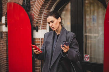 Stylish woman look calm serious holding a smartphone and credit card while making a mobile payment outdoors. Cashless payment, fintech, digital wallet and modern urban lifestyle concept.