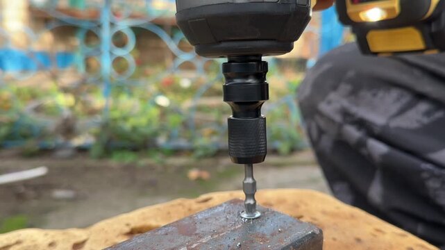 cordless drill with Phillips bit tighten screw in rusty metal frame close view