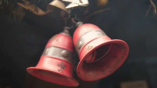Close-up of rustic red metal bells hanging outdoors. Decorative vintage bells suitable for holiday or winter market themes