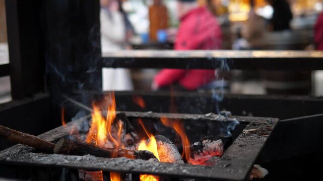 A small open fire at a Christmas market. The glowing flames create a cozy contrast to the cold winter atmosphere surrounding the festive outdoor event