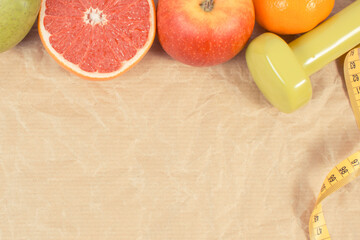 Ripe fruits, tape measure and dumbbells for fitness. Healthy lifestyle. Fruits as source minerals and vitamins. Place for text