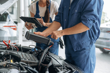 Obraz premium Particle close up view of male and female mechanics that are repairing the car