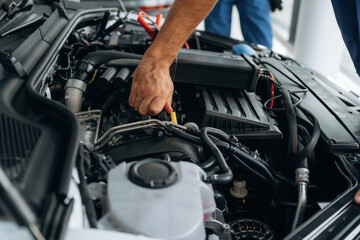 Fixing the car, hood is opened. Close up view of male service station worker at job