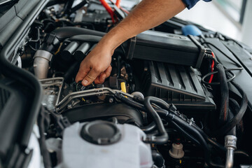 Fixing the car, hood is opened. Close up view of male service station worker at job