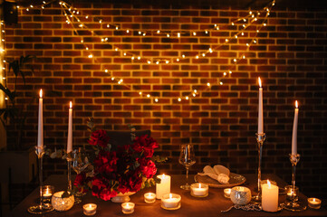 Candlelight date in restaurant. Champagne glasses, bouquet flowers. Romantic dinner setup at night. Table setting for couple, Valentine's Day evening, burning candles for surprise marriage proposal.