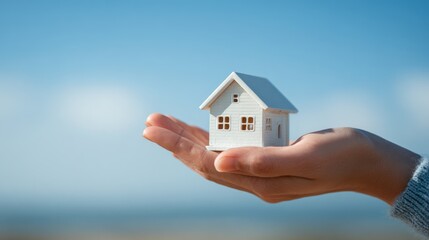 Hand holding a small model house is a concept for real estate investment and home mortgage loan business