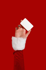 Womans hand in Santa sleeve holding blank card on red background. Christmas mockup.
