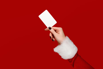 Womans hand in Santa sleeve holding blank card on red background. Christmas mockup.