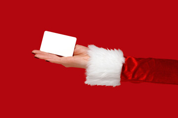 Womans hand in Santa sleeve holding blank card on red background. Christmas mockup.