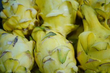 artichoke on a market stall. A yellow dragon fruit picked from an old orchard is in poor condition. It must be peeled and washed thoroughly before eating.