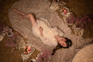 Dreamy woman lying among flowers in a soft vintage setting