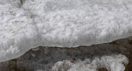 Detailed close-up view of a snow layer showcasing unique crystalline patterns and textures, highlighting the beauty of winter's natural formations and the interplay of light on the surface