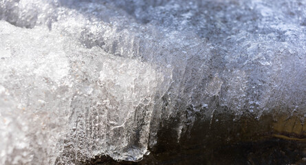 Detailed close-up of ice formation on a frozen surface, showcasing intricate textures and natural patterns, reflecting light and creating a serene winter atmosphere