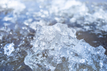Detailed close-up view of ice crystals glistening under sunlight, creating a beautiful texture on the water surface, showcasing the interplay of light and nature's artistry