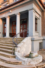 Wejście do zabytkowego budynku z zakrzywionymi schodami, kolumnami i ozdobną balustradą. Pałac Pogrzebień – neorenesansowy pałac z XIX wieku. © Pol Badger