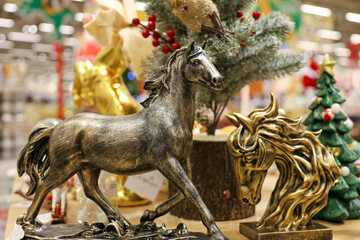 Symbol of the year 2026, metal toy horses on blurred festive lights background. New Year souvenirs in a superstore