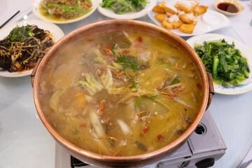 Spicy fish soup hot pot simmering broth cabbage vegetable platter communal meal