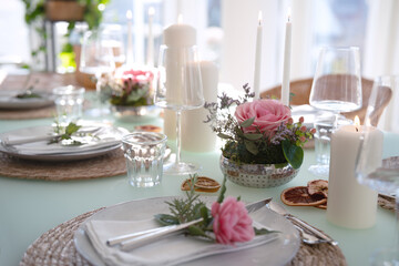 Wedding table decorated with pink roses. Festive set table for a wedding dinner. Bright, elegant restaurant background with short depth of field.