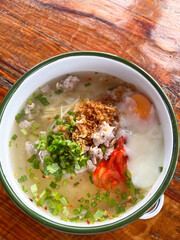 Seasoned rice porridge with minced pork, soft egg, herbs and chili, comforting savory breakfast soup with crispy garlic