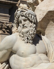 Naklejka premium Statue of a Naked Bearded Man Symbolizing the Ganges Close Up in Rome, Piazza Navona, Italy