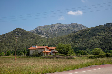 Cozy White House With Red Roof In A Rural Landscape With Mountain Backdrop