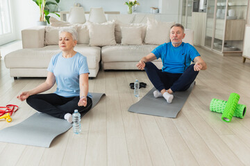 Yoga mindfulness meditation. Senior adult mature couple practicing yoga at home. Mid age old husband wife sitting in lotus pose on yoga mat meditating relaxing. Family doing breathing practice