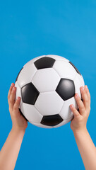Child hands holding soccer ball on blue background