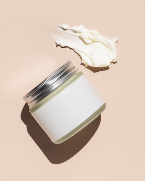 Jar of beef tallow skincare with texture product swipe on tan background