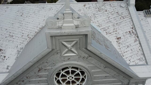 Close-up view of a Celtic cross and a rose window, a circular Gothic-style window, all covered with aluminum sheeting adorning the Saint-Octave-de-M&eacute;tis Church, Quebec, Canada, 2025.